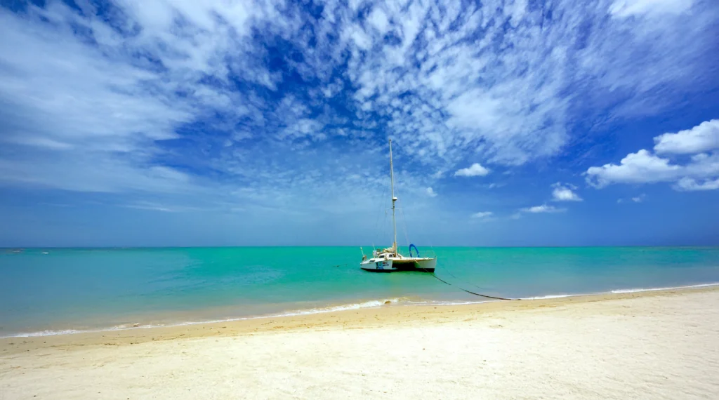 Fishing boat anchored on tropical beach with turquoise water and blue sky in Miami coast